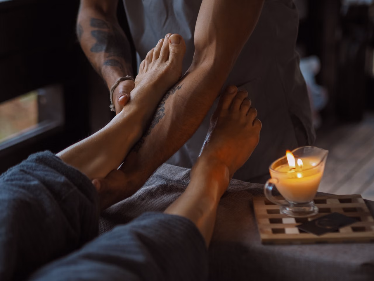 hands resting calmly beside a candle in a peaceful treatment space